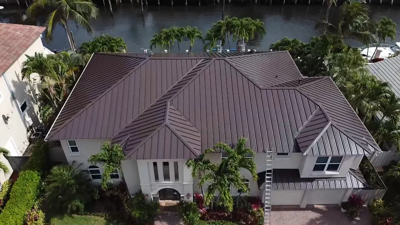 Aerial view of a brown standing-seam metal roof on a two-story waterfront home.