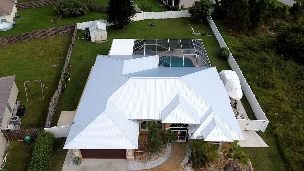 Aerial view of a bright white metal roof with intersecting hips and covered entries.