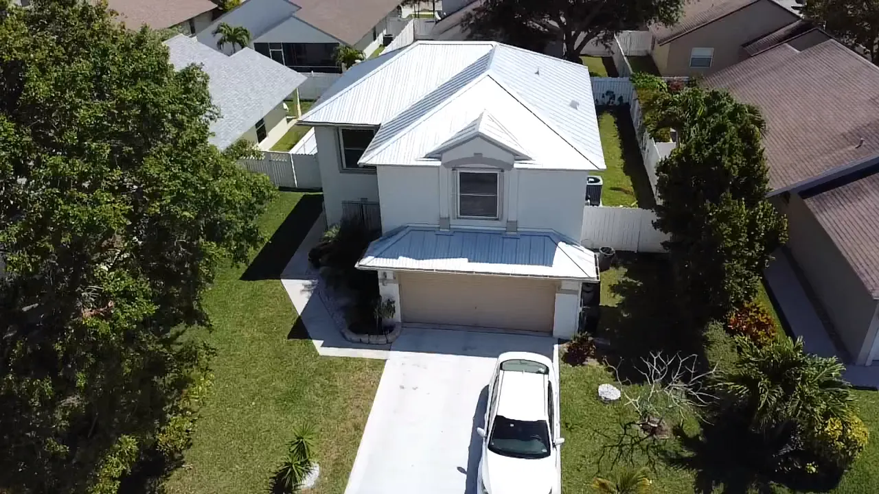 Front aerial view of a two-story home with a bright white metal roof.