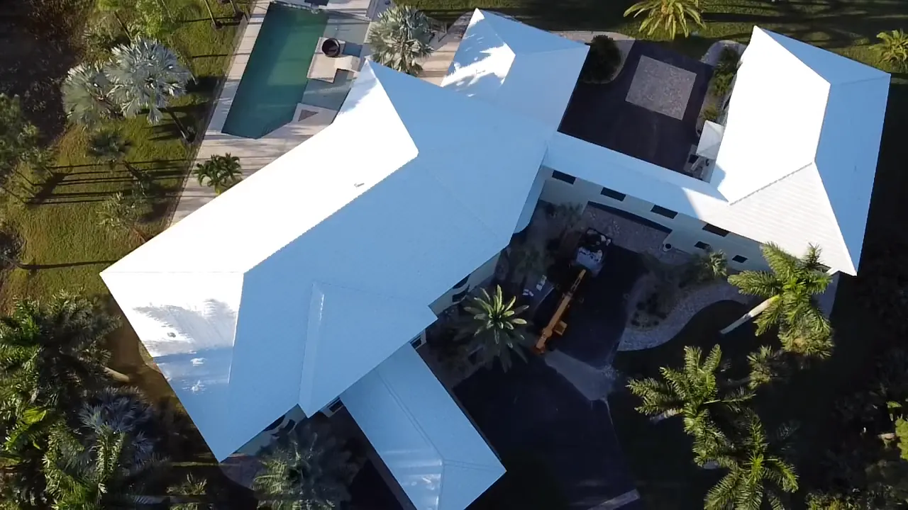 Aerial view of a large home with a completed white metal roof and multiple wings.