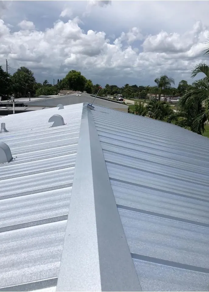 Close view of a white metal roof ridge, fasteners, and panel seams.