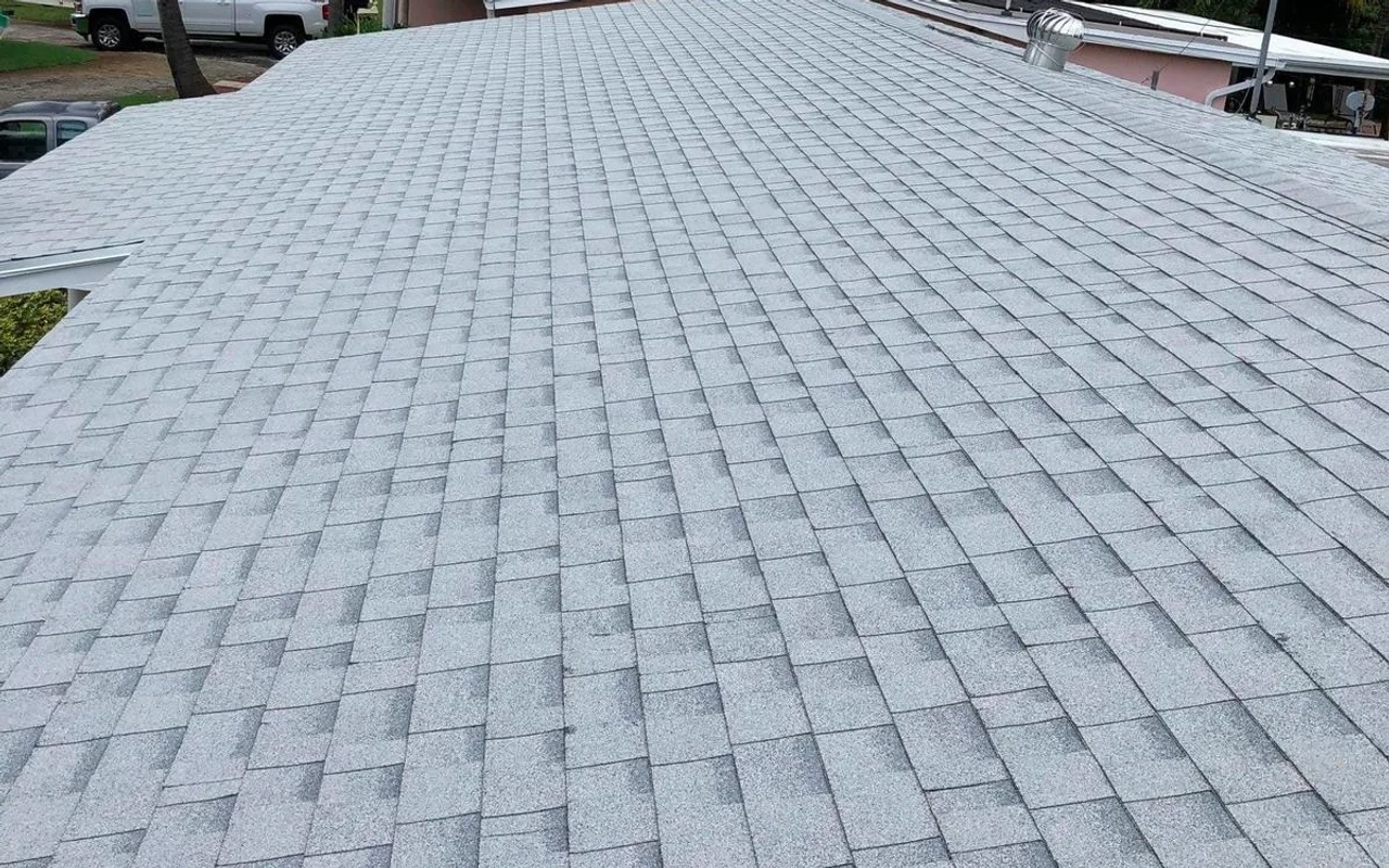Finished light-gray shingle roof with multiple slopes and a turbine vent.
