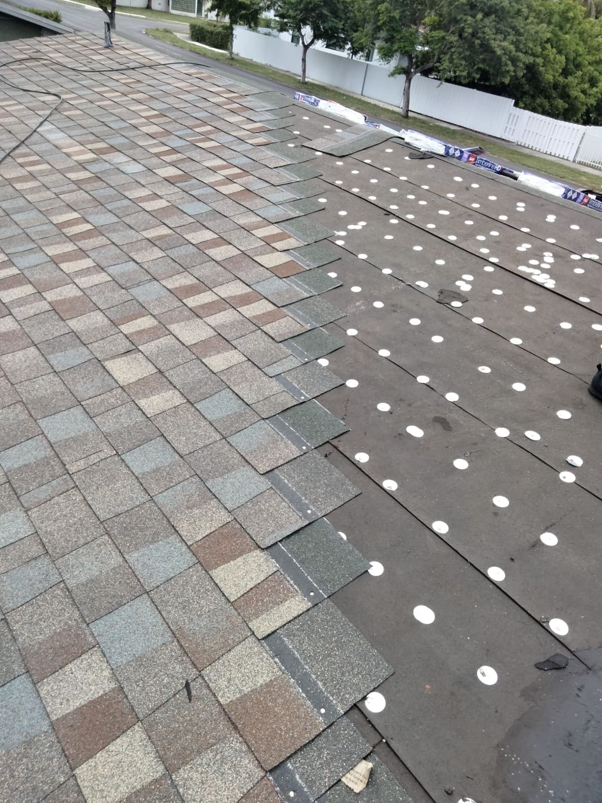 Asphalt shingles being installed over number 30 felt secured with round metal tin caps and roofing nails.