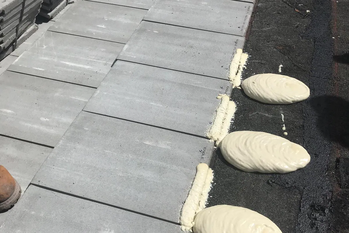 Flat-profile concrete roof tile installation with medium APOC Polyset foam adhesive paddies on underlayment.