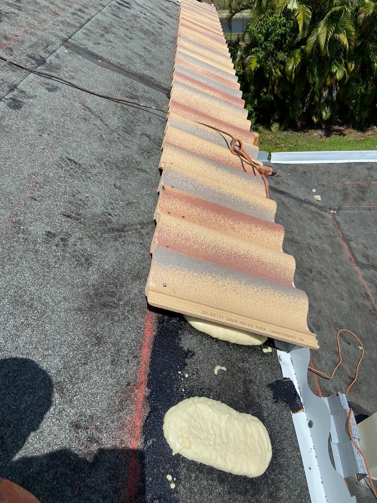 Villa 900 concrete roof tiles being set over foam adhesive at the eave with underlayment and a metal eave closure visible.